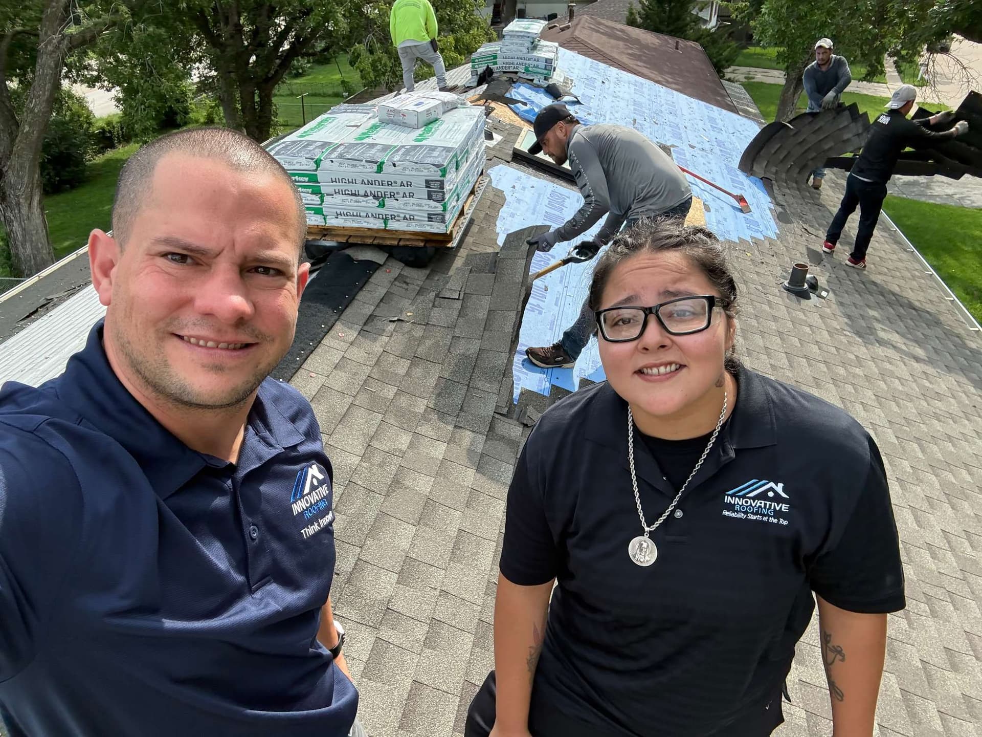Two Innovative Roofing team members on a residential roof while the crew installs new shingles behind them