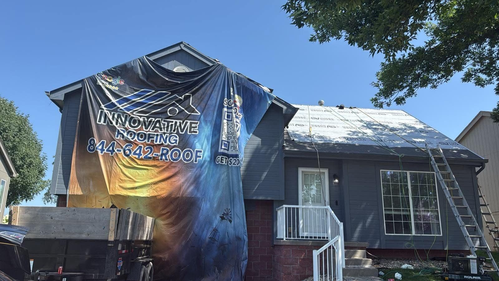 Split-level home mid roof replacement with Innovative Roofing banner and white underlayment on the deck
