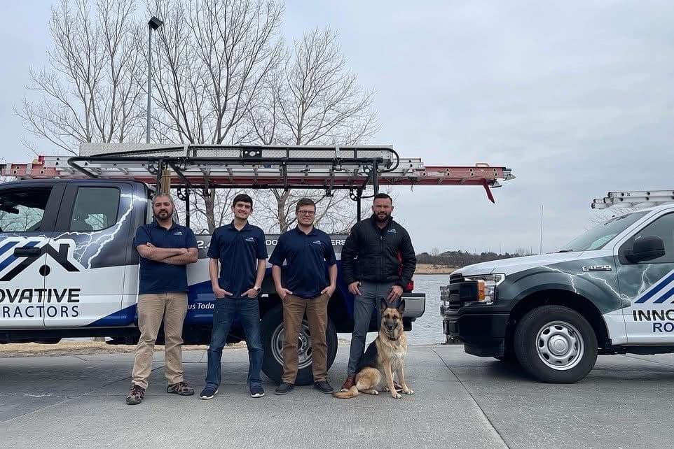 Innovative Roofing crew posing beside wrapped Ford F-150 trucks with ladders on the rack