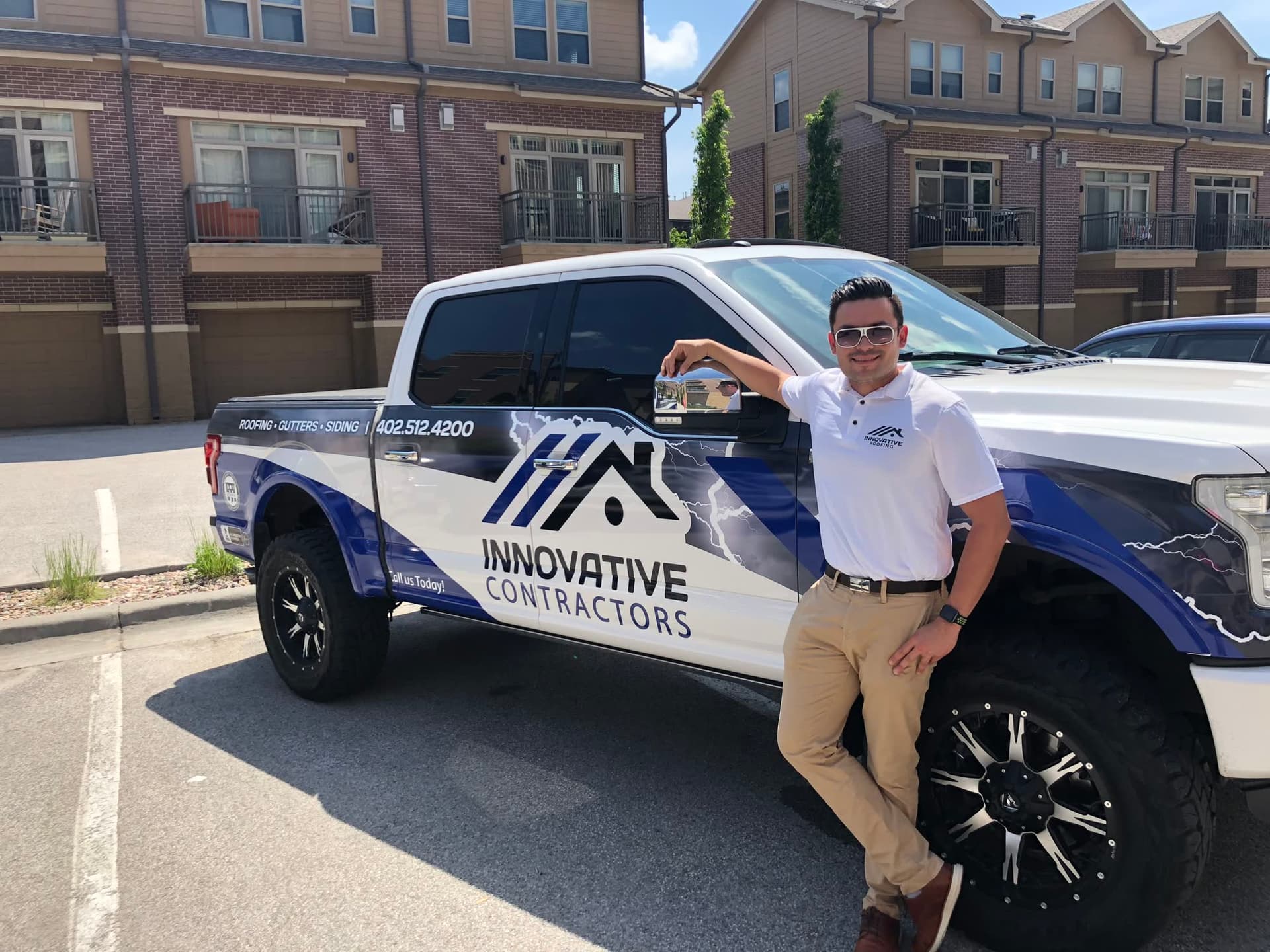 Innovative Roofing team member beside a wrapped Ford F-150 showing roofing, gutters, and siding branding