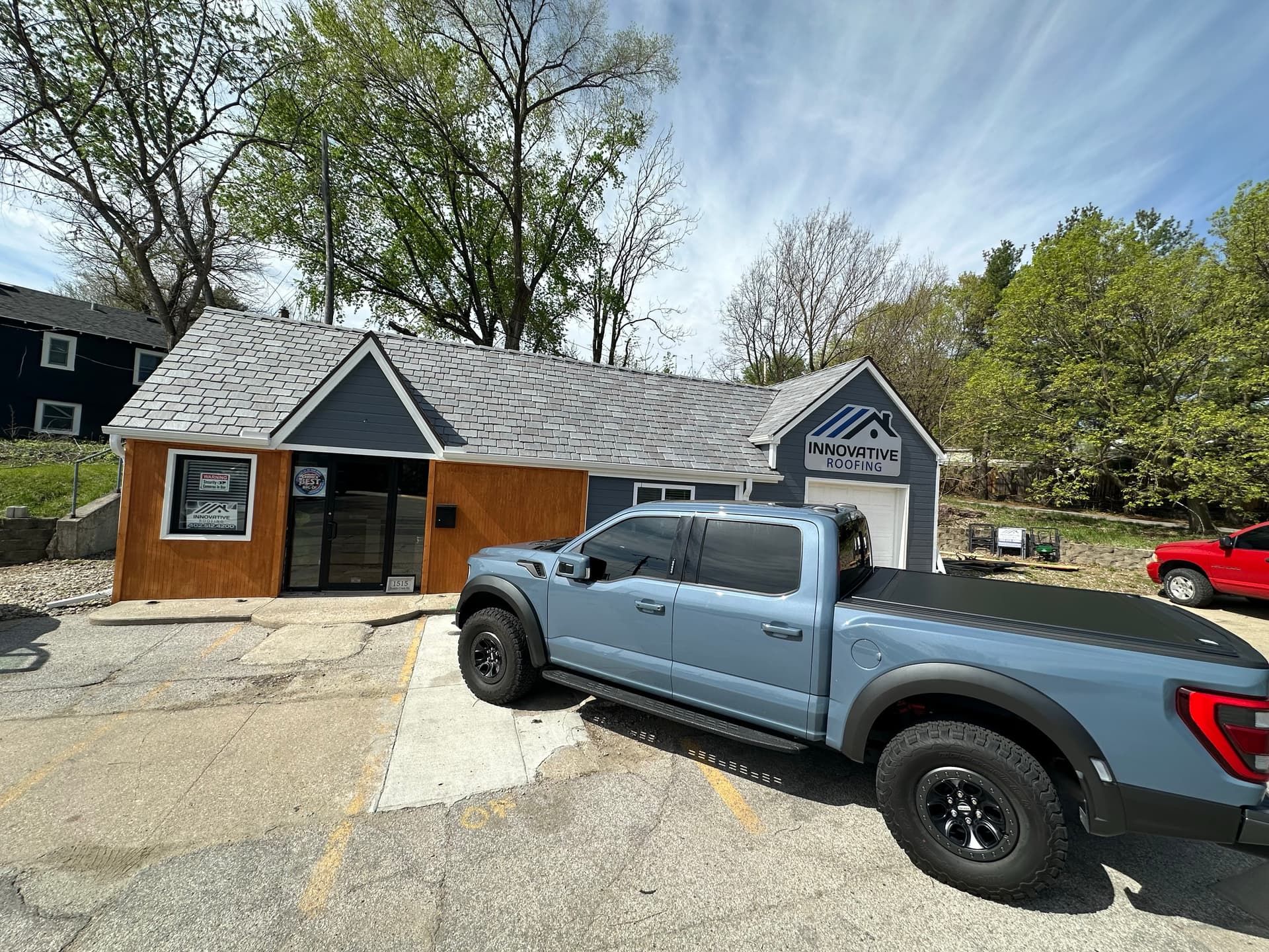 Innovative Roofing Omaha office building with company sign and light blue Ford F-150 Raptor in the parking lot