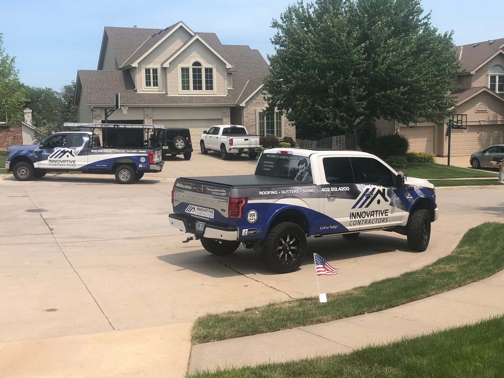 Two Innovative Contractors wrapped pickup trucks parked in a residential driveway with ladder rack