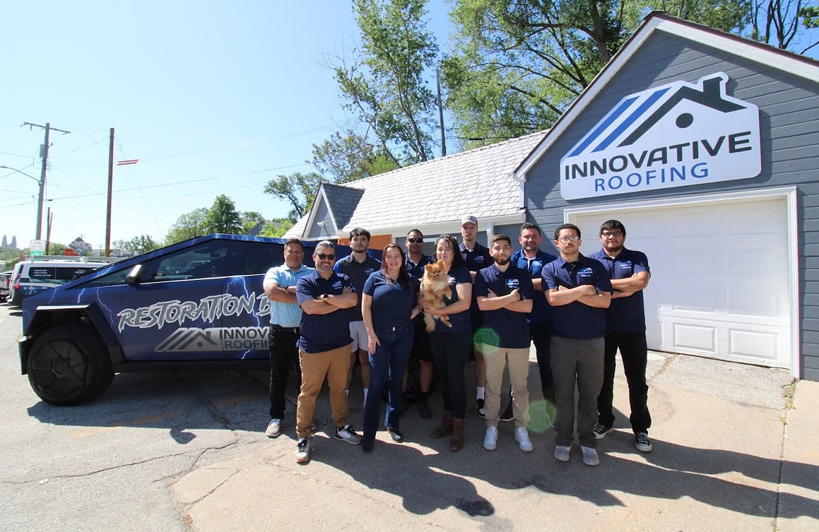 Innovative Roofing team in matching polos posing at the office with the Restoration Beast Cybertruck and the company dog