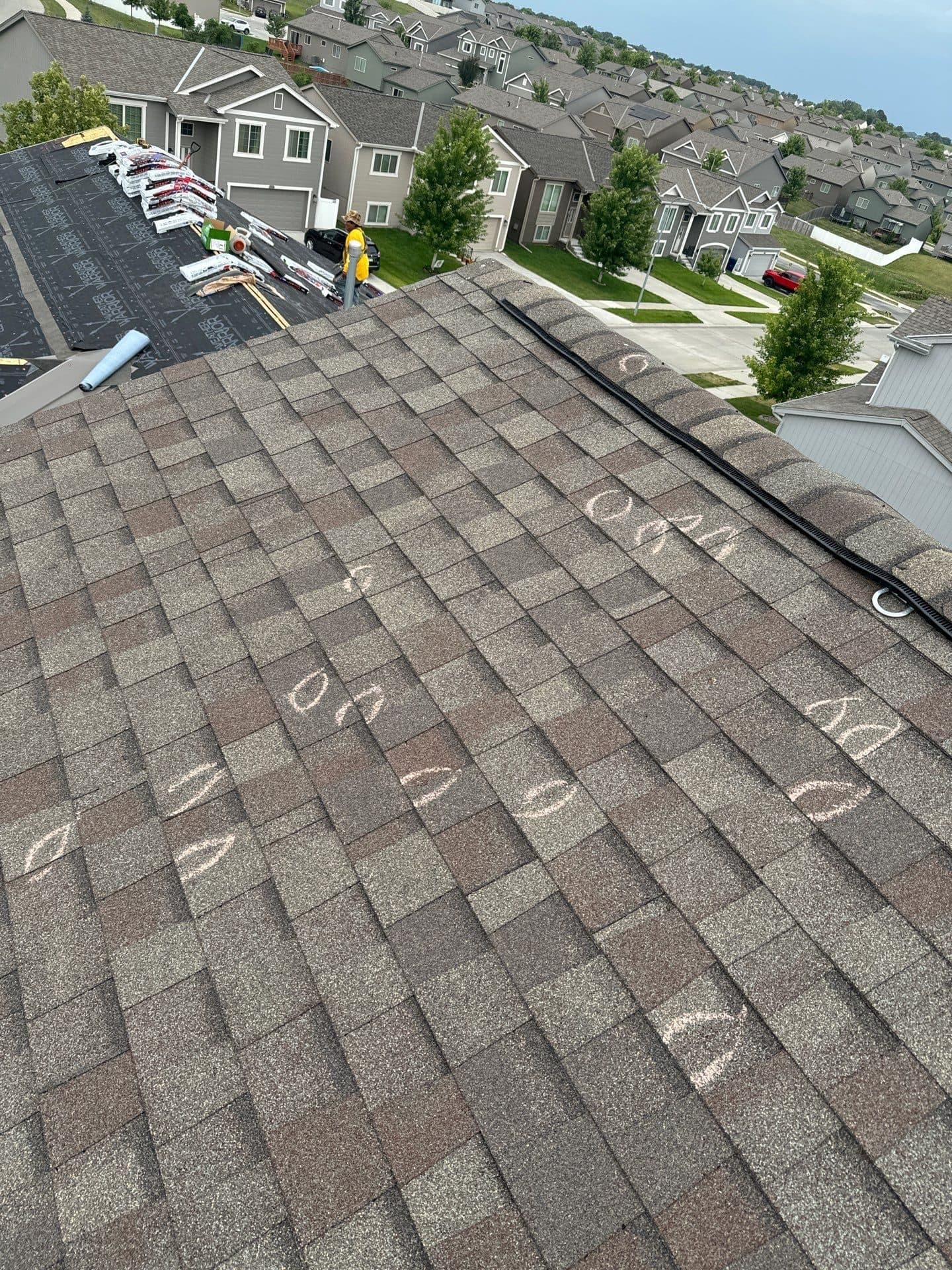 Innovative Roofing Kansas City job — hail hits chalk-marked on a shingle roof during inspection, with new underlayment going on