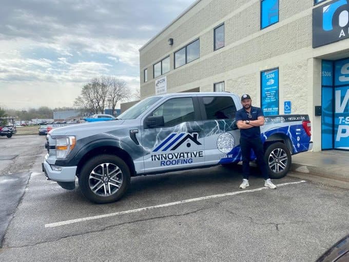 Innovative Roofing team member standing beside a wrapped Ford F-150 with company logo and QR code