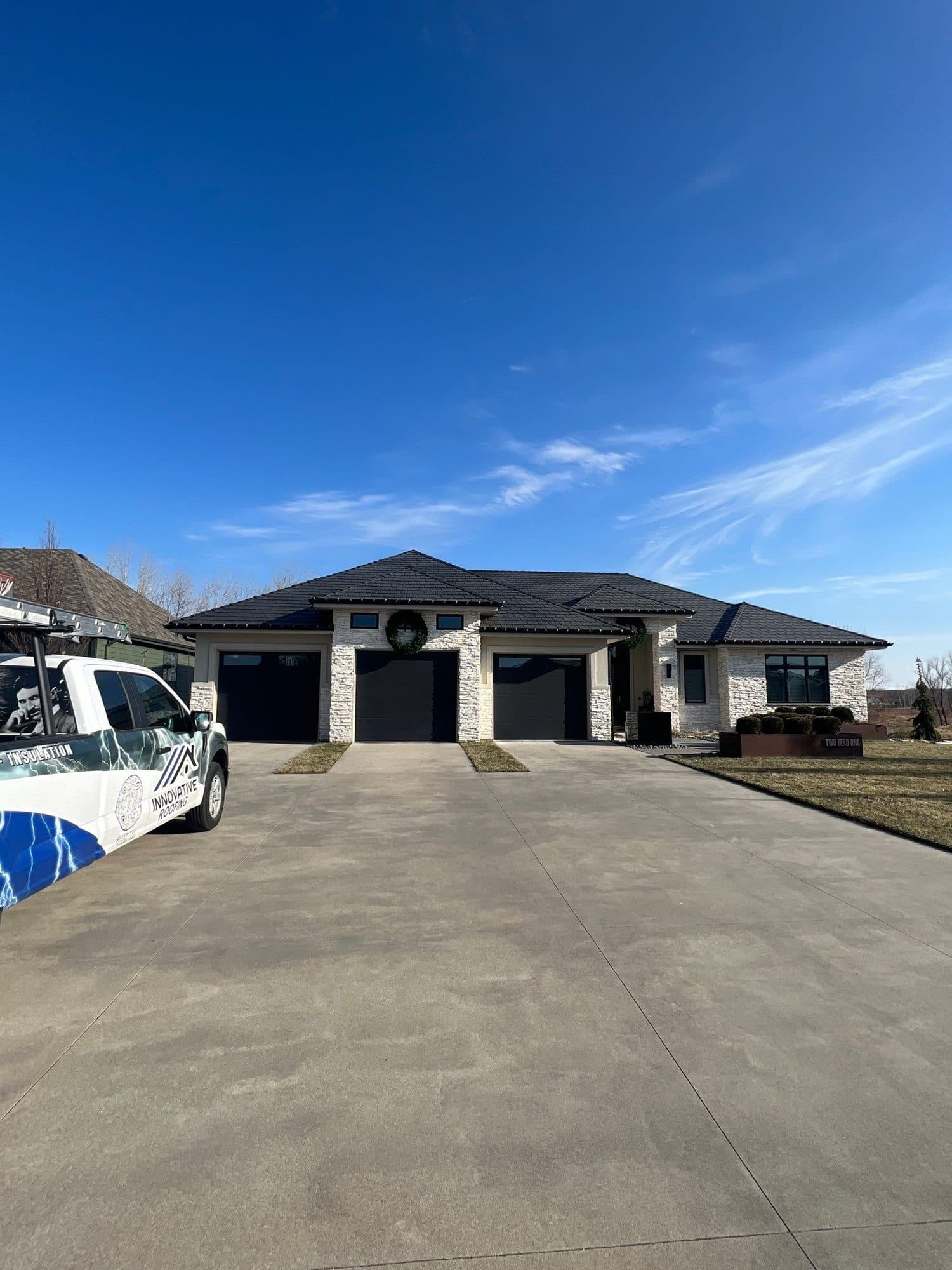 Modern finished home with a dark gray roof and a white Innovative Roofing van in the driveway