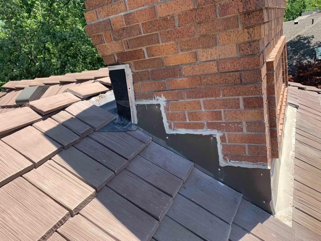 Metal flashing and shingle work around a brick chimney