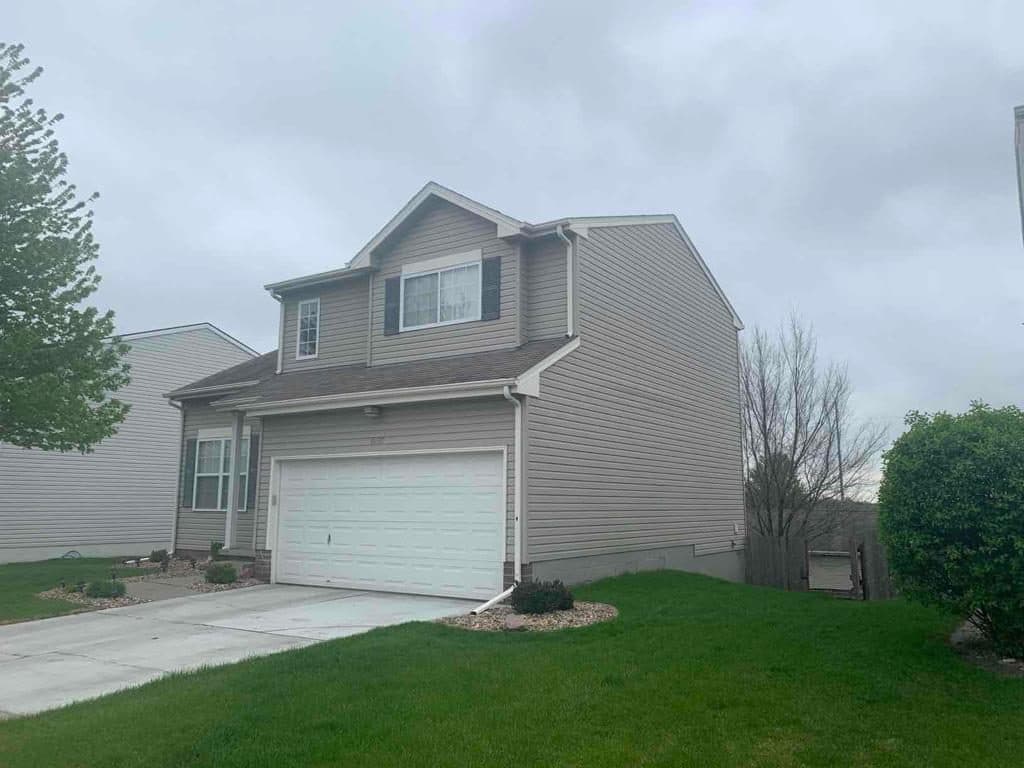Two-story tan home with a finished gray roof from the street