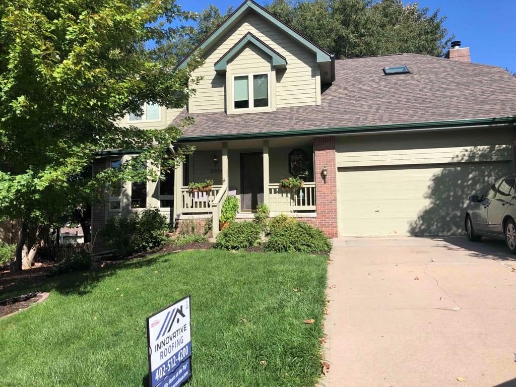 Two-story beige suburban home with a finished gray roof and two-car garage