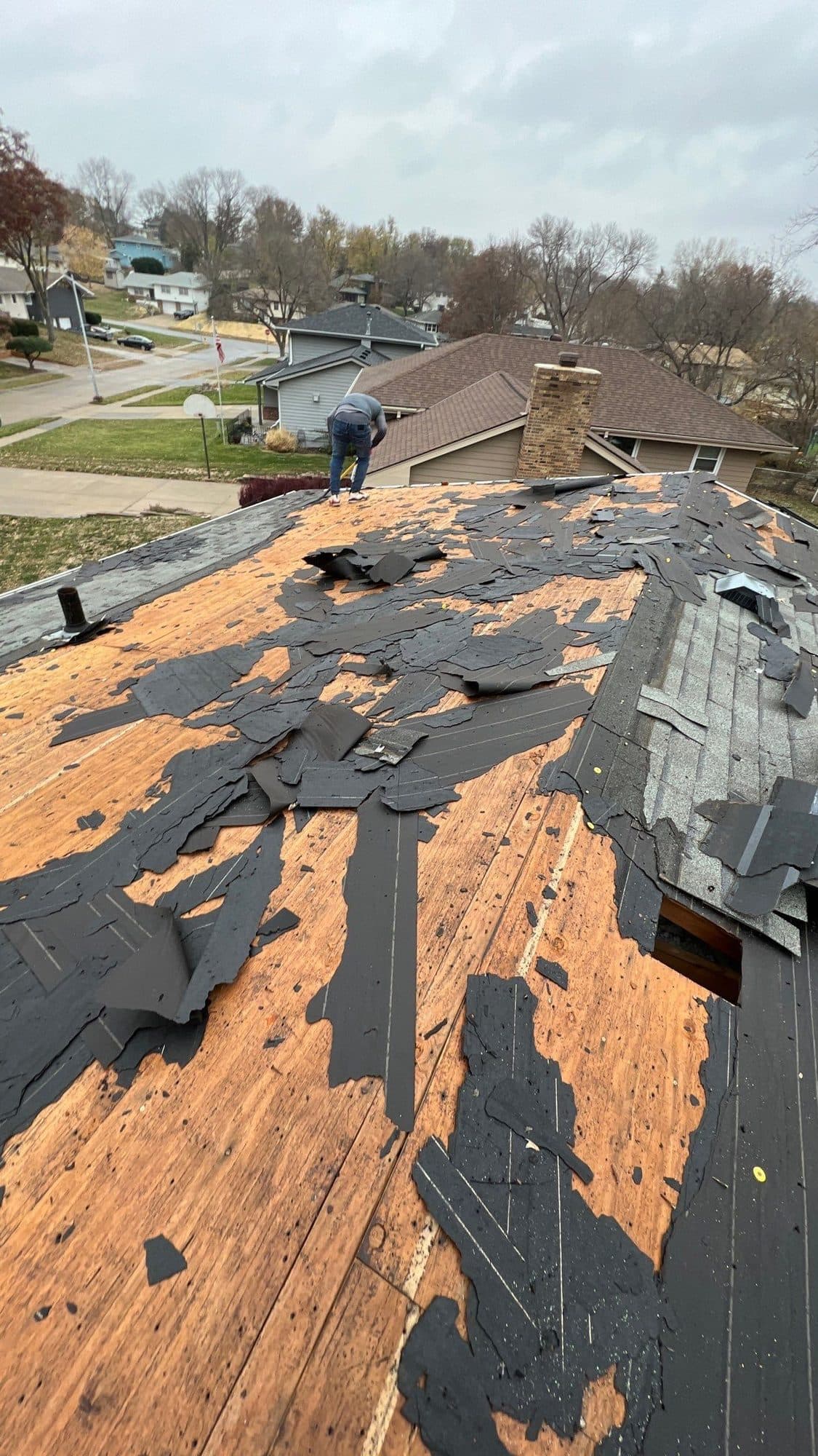 Overhead tear-off in progress with old shingles removed and wood deck exposed