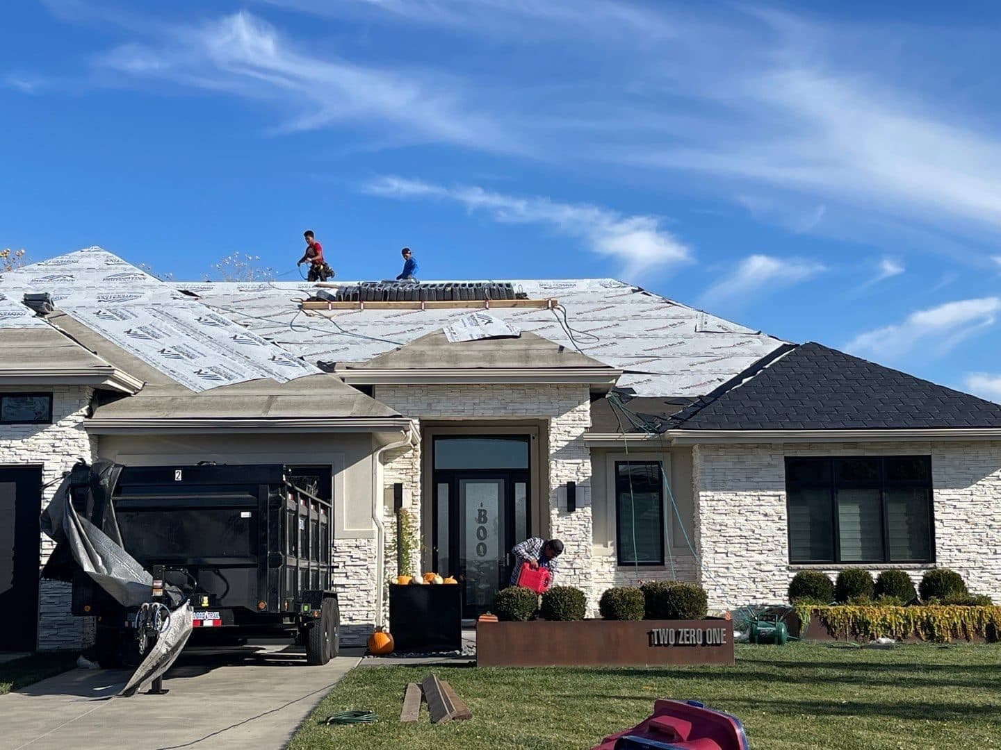 White stone home mid roof replacement with old roof removed and underlayment exposed