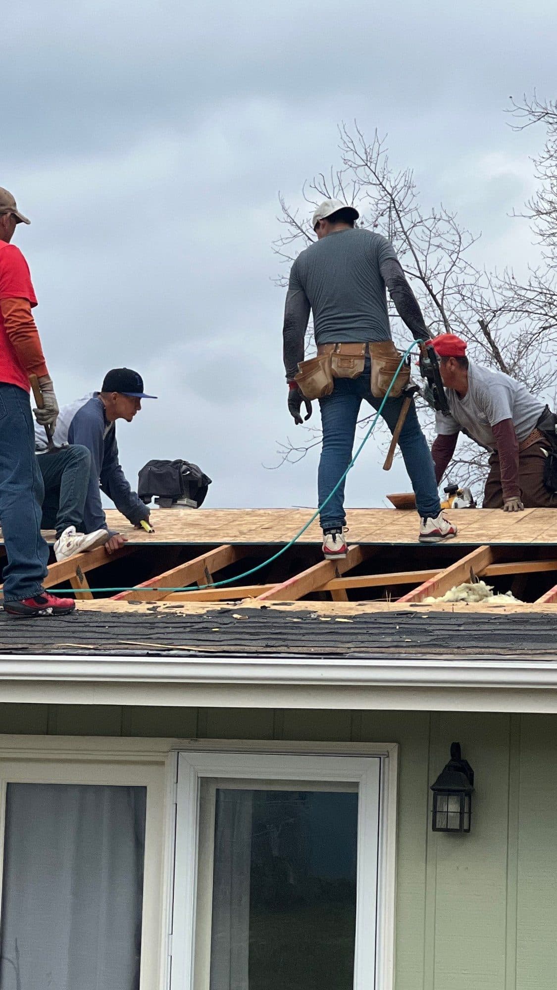 Three roofers tearing off old roofing material on a residential job