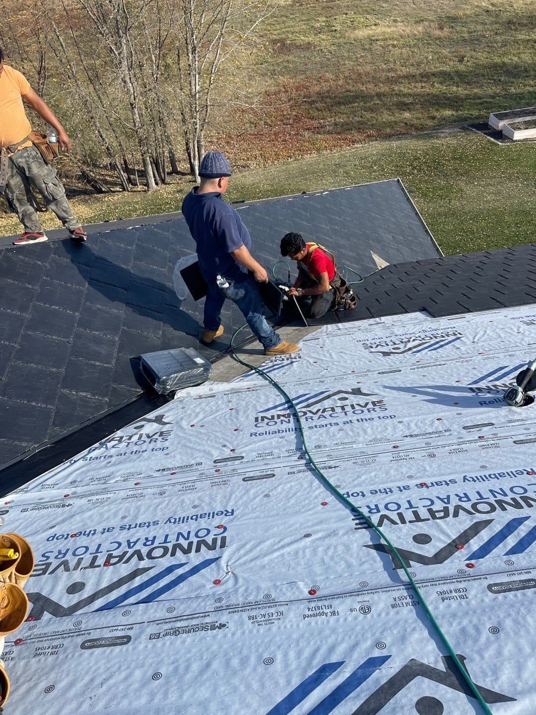 Crew installing roofing over Innovative Roofing branded blue underlayment on a residential roof