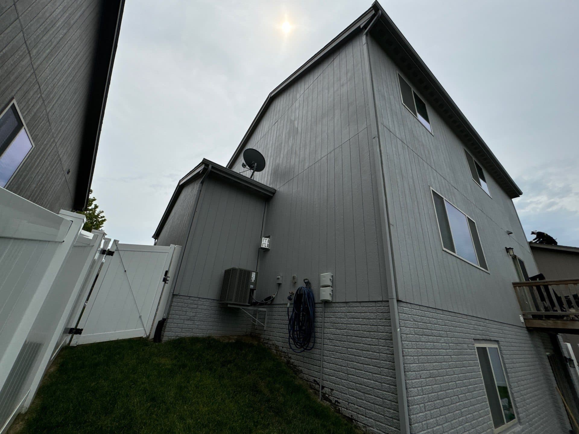 Looking up at the roofline and gutters on a tall gray-sided home