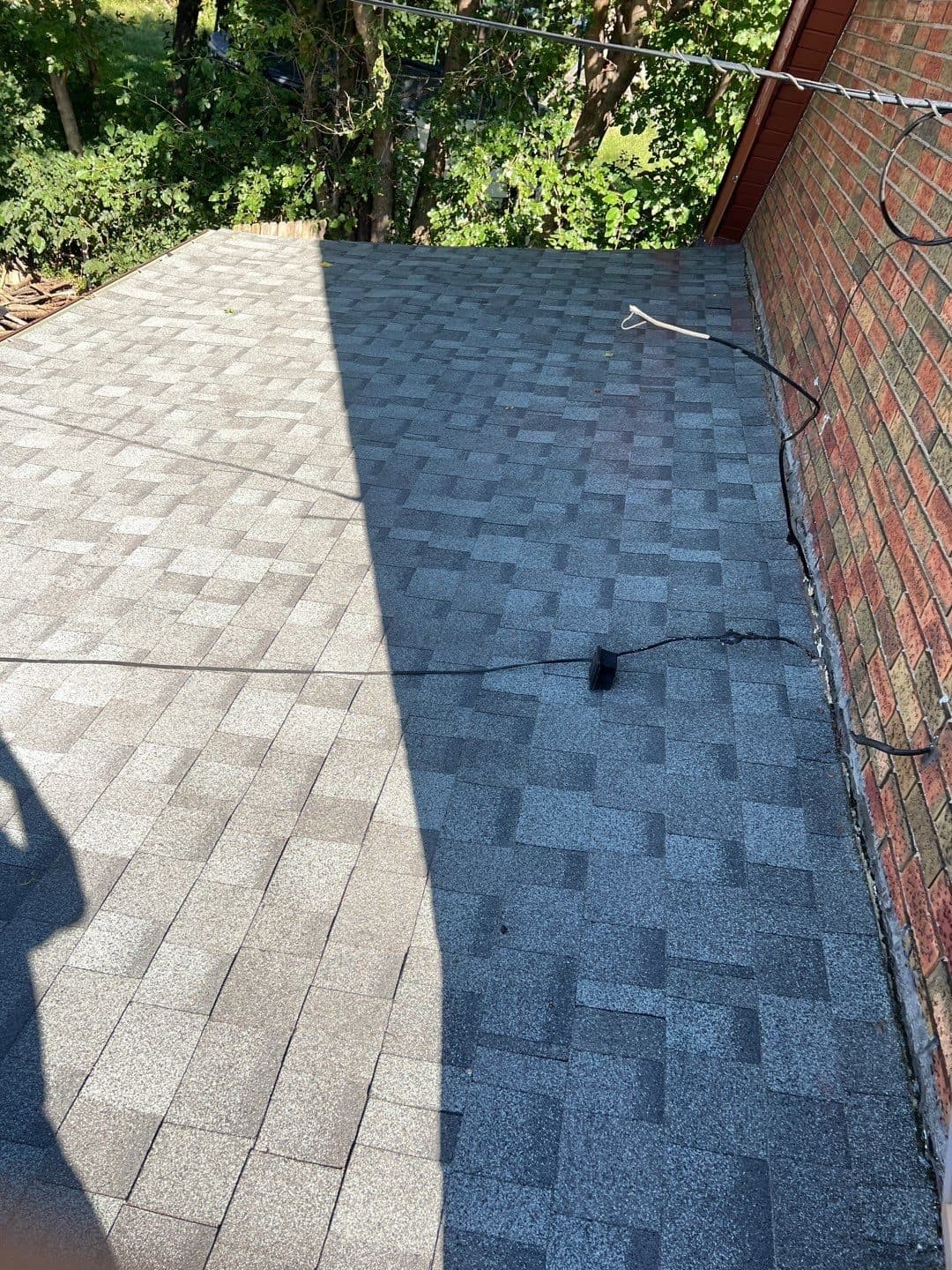 New gray shingles meeting a red brick wall with clean flashing