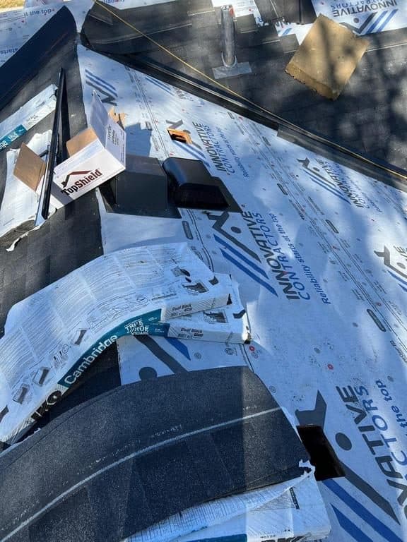 Roof under construction with blue Innovative Roofing branded underlayment under new shingles