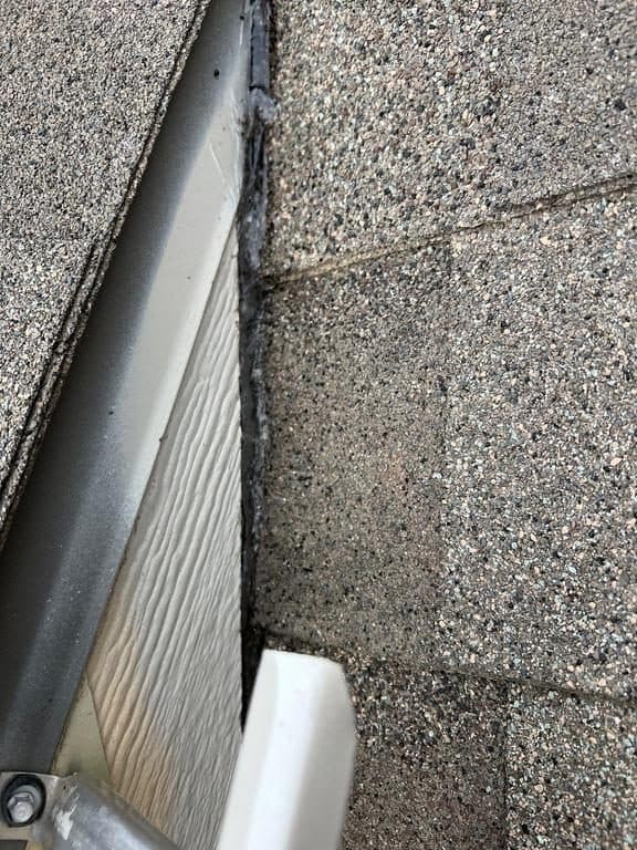 Looking down into a clean white gutter along a new shingle roof edge