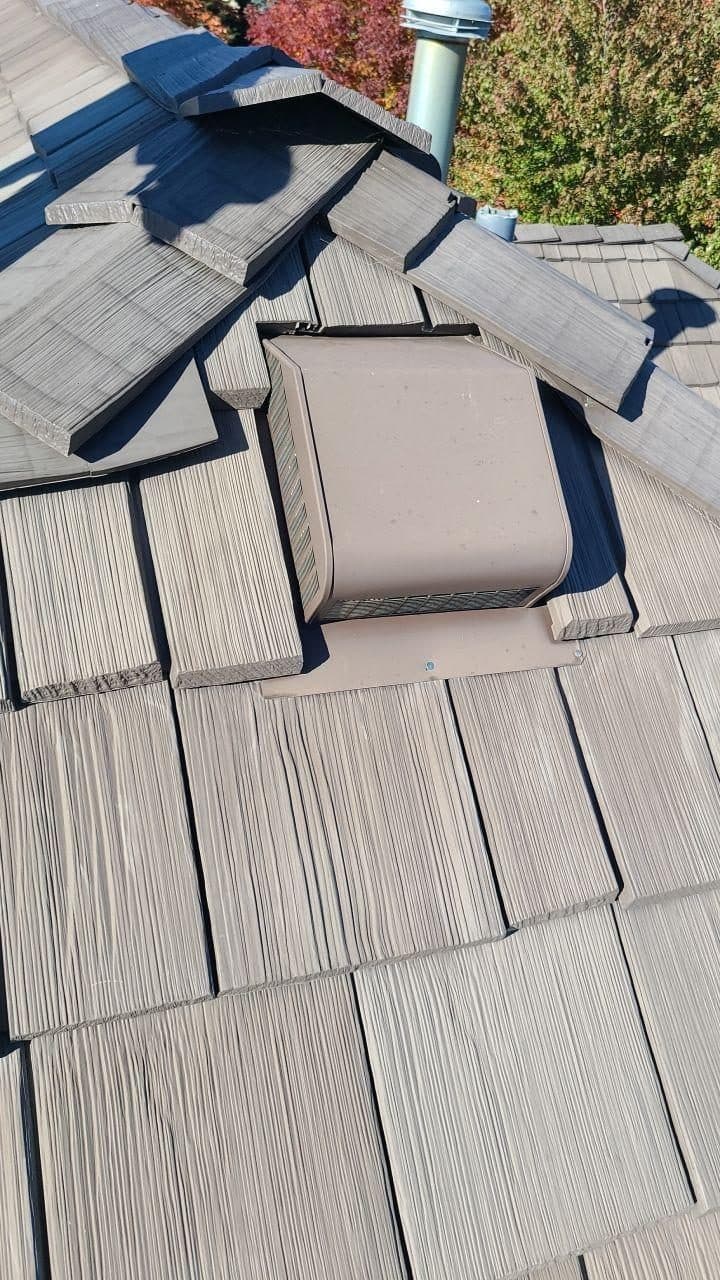 Close-up of gray shingles around a square roof vent