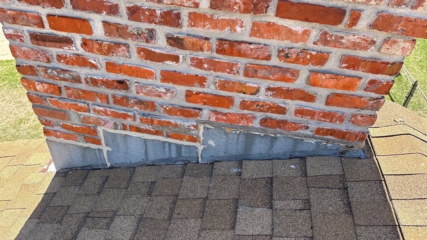 Gray shingles flashed cleanly against a red brick chimney