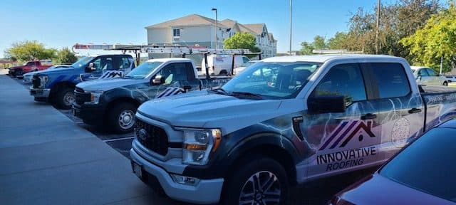 Row of Innovative Roofing branded Ford trucks with company wraps parked ready for jobs