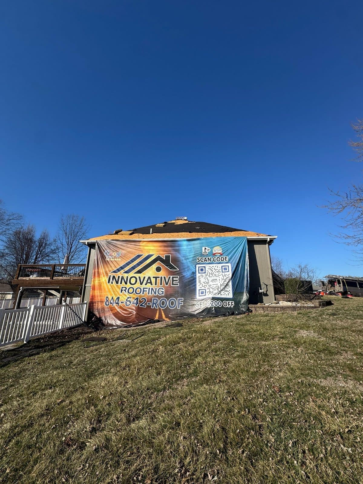 Residential roof replacement in progress with a large Innovative Roofing job-site banner